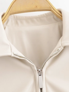 Detail view of the classic lapel and metal zipper on a cream white faux leather jacket