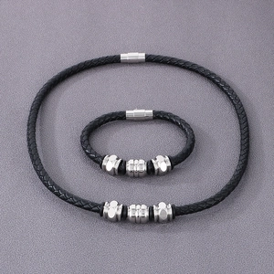 Detail of black braided leather bracelet and necklace set with silver magnetic clasps