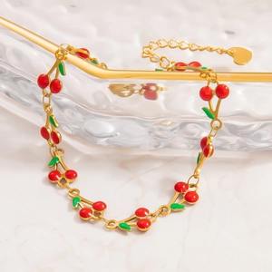 Detail of 18k gold plated bracelet with red enamel cherries and a small heart charm