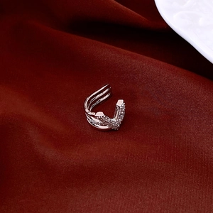 Macro shot of silver V-shaped ear cuff with sparkling zircons on red silk fabric