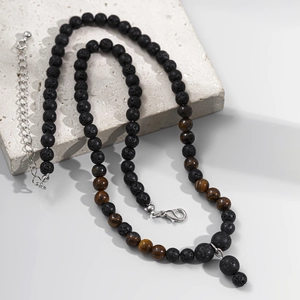 Close-up of hip hop men's necklace with tiger eye and black lava beads on stone