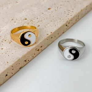 Detailed view of gold and silver stainless steel rings with Yin Yang symbol on stone surface