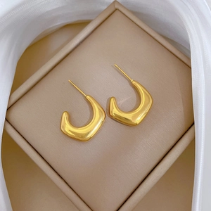 Minimalist golden U-shaped titanium steel earrings displayed on white silk in a jewelry box