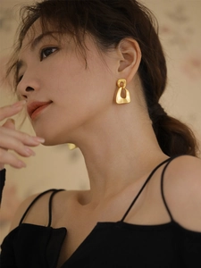 Elegant close-up of matte gold irregular geometric hollow drop earrings on an Asian model.