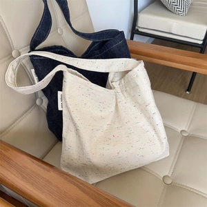 Dettaglio ravvicinato di borse tote in denim blu e tela color crema con etichette tessute