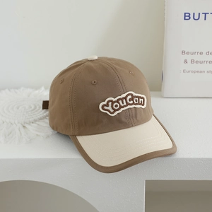 Détail de la broderie You Can et coutures précises sur une casquette bicolore en coton