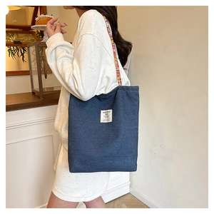 Détail du grand sac cabas en denim bleu foncé avec bandoulière colorée de style ethnique