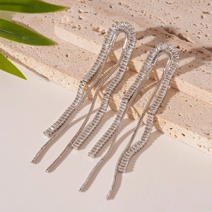 Macro detail of U-shaped silver zircon earrings with long cascading tassels on stone