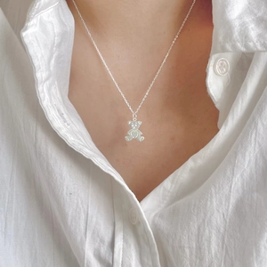 Minimalist 925 sterling silver bear pendant necklace on model with heart detail