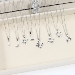 Detail of silver letter pendants I-P with black outlines on velvet display