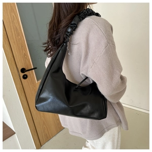 Detail of the pleated handle and matte black leather texture on the hobo cloud bag