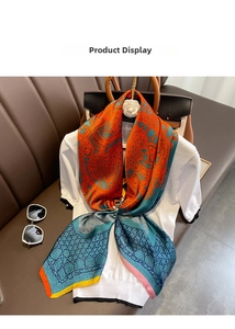 Détail d'un foulard en soie aux motifs abstraits orange et cyan drapé sur un t-shirt blanc