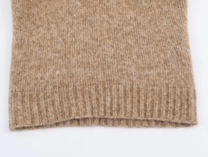 Gros plan détaillé de l'ourlet de la robe en maille camel avec texture côtelée et laine