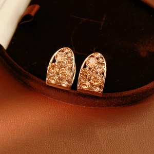 Gros plan sur les boucles d'oreilles en or rose serties de cristaux champagne