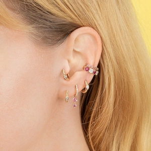 Gros plan de boucles d'oreilles dorées avec zircons roses et blancs en marquise