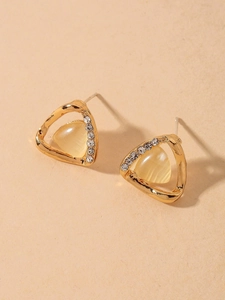 Macro detail of golden triangular earring with cat eye stone and tiny rhinestones