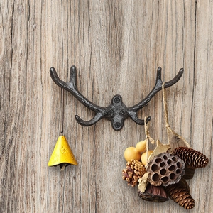 Rustic cast iron antler wall hook with vintage bronze finish on vertical wood texture