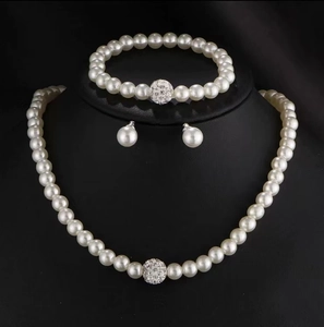 Detail of faux pearl jewelry set featuring a sparkling rhinestone ball on necklace and bracelet