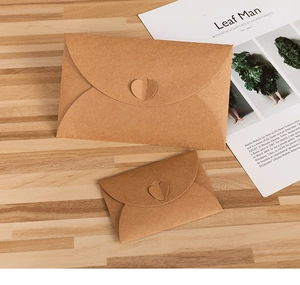 Detail of two vintage brown kraft paper envelopes with heart-shaped clasps on wood
