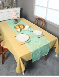 Detail of mint green hollow lace table runner with floral patterns over ginger table cloth