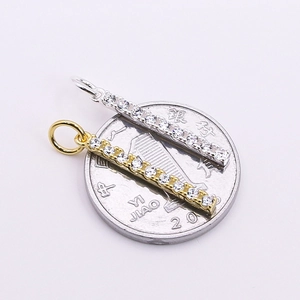 Micro-paved zirconia bar pendant in gold and silver finish shown with a coin for scale
