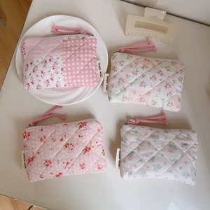 Detail of four quilted floral mini coin purses with zipper pulls and side woven labels
