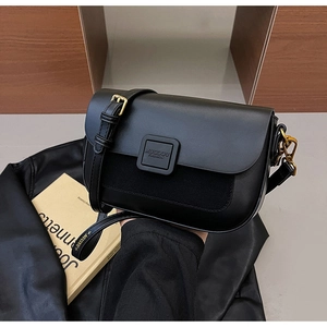 Detail of black crossbody bag featuring mixed leather texture and golden magnetic buckle