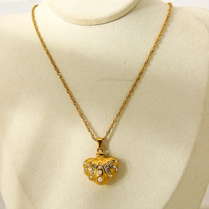 Detail of gold shell pendant necklace with cubic zirconia and pearl on a jewelry bust
