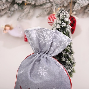 Christmas drawstring gift bag with grey snowflake pattern and red Merry text in a festive setting