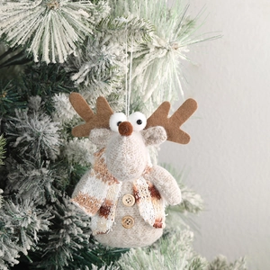 Cute plush reindeer Christmas ornament with brown plaid scarf on snowy tree branch
