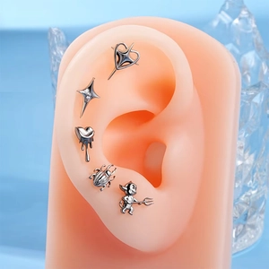 Detailed set of G23 titanium studs featuring heart and star shapes on a silicone ear model