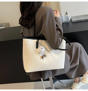 Borsa tote minimalista bianco crema con bordi neri e ciondolo a mostro di peluche