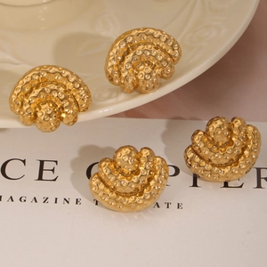 Golden fan-shaped geometric earrings with vintage hammered texture on a ceramic plate