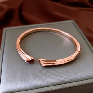 Bracelet jonc ouvert en or rose avec design double gourde sur boîte à bijoux