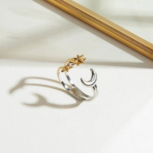 Macro detail of two-layer steel ring with gold stars and silver moon on white surface