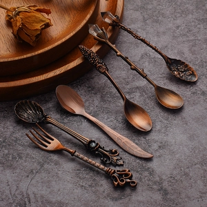 6-piece set of vintage bronze spoons and forks with relief patterns on dark background