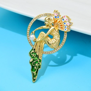 Retro fairy brooch with gold metal, white pearl and colorful wings on a blue background