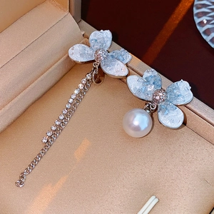 Close-up of asymmetric butterfly earrings with blue crystals, pearls and rhinestone tassels
