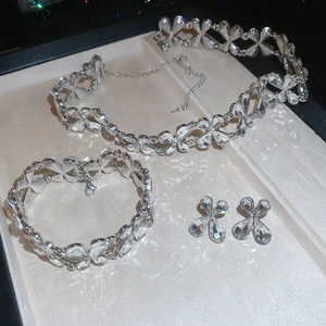 Detailed set of silver floral crystal necklace, bracelet, and earrings on a jewelry tray