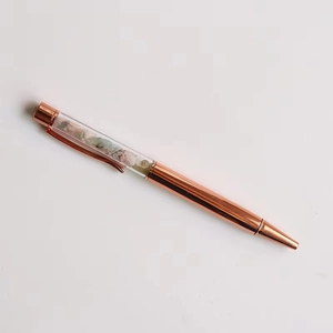 Top view of rose gold metal ballpoint pen filled with colorful crushed crystal stones