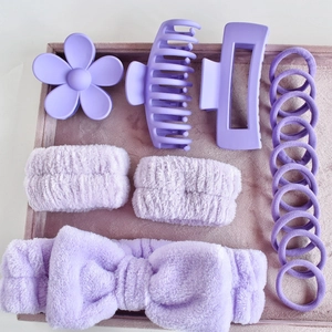Flat lay of purple hair accessory set featuring matte clips, plush headband and elastic bands