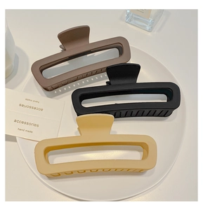 Three large matte rectangular hair claws in brown, black and beige on a white plate