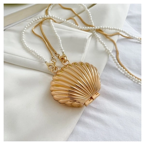 Detail of gold shell evening bag with pearl chain and metal snake chain accessories