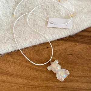 Macro shot of iridescent resin bear pendant with white cord and gold adjustable bead