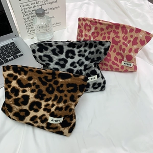 Makroaufnahme von strukturierten Make-up-Taschen aus Cord mit Leopardenmuster im Bett