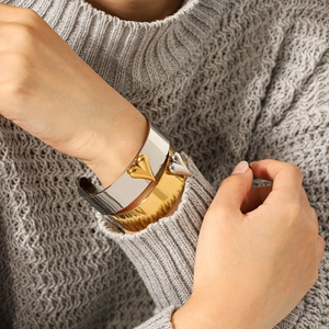 Macro shot of a two-tone gold and silver heart-shaped open bangle on woman's wrist