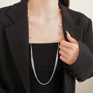 Detail view of multilayer pearl necklace with silver snake chain tassels on model