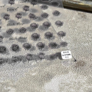 Close-up of ultra-thin 5D nail stickers featuring black roses and artistic typography
