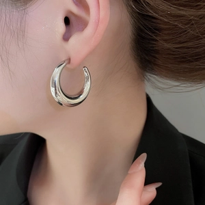 Close-up of polished silver C-shaped hoop earrings featuring a minimalist metallic finish