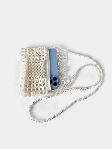 Detail of a white handmade beaded crossbody bag with pearls and a phone inside